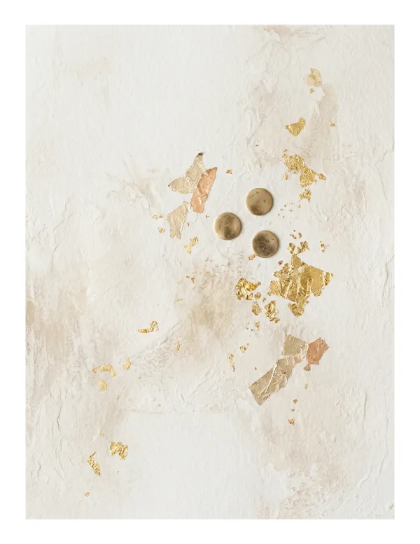 Abstract textured background with scattered gold leaf flakes and four small metallic circular elements.